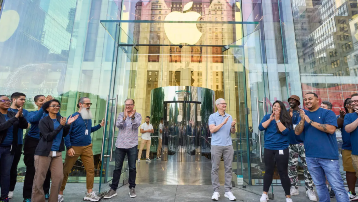 Apple Storeのガラス張りの入口前で拍手するスタッフたちの画像